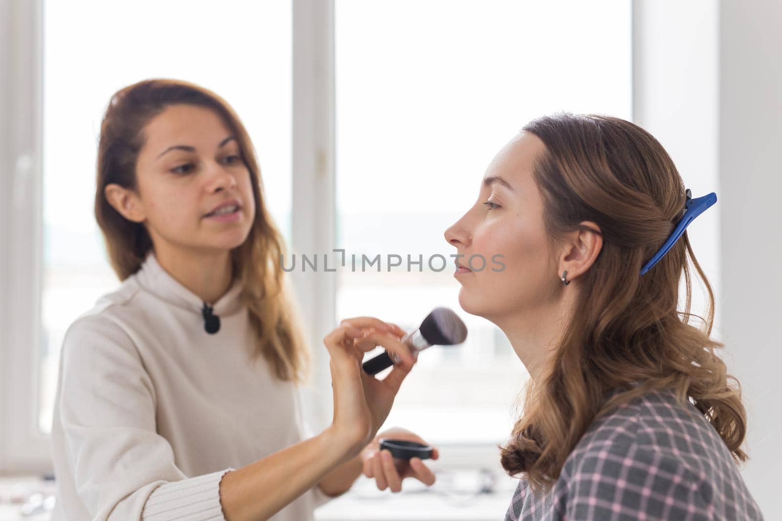 Beauty and cosmetics concept - Makeup artist doing professional make up of young woman.