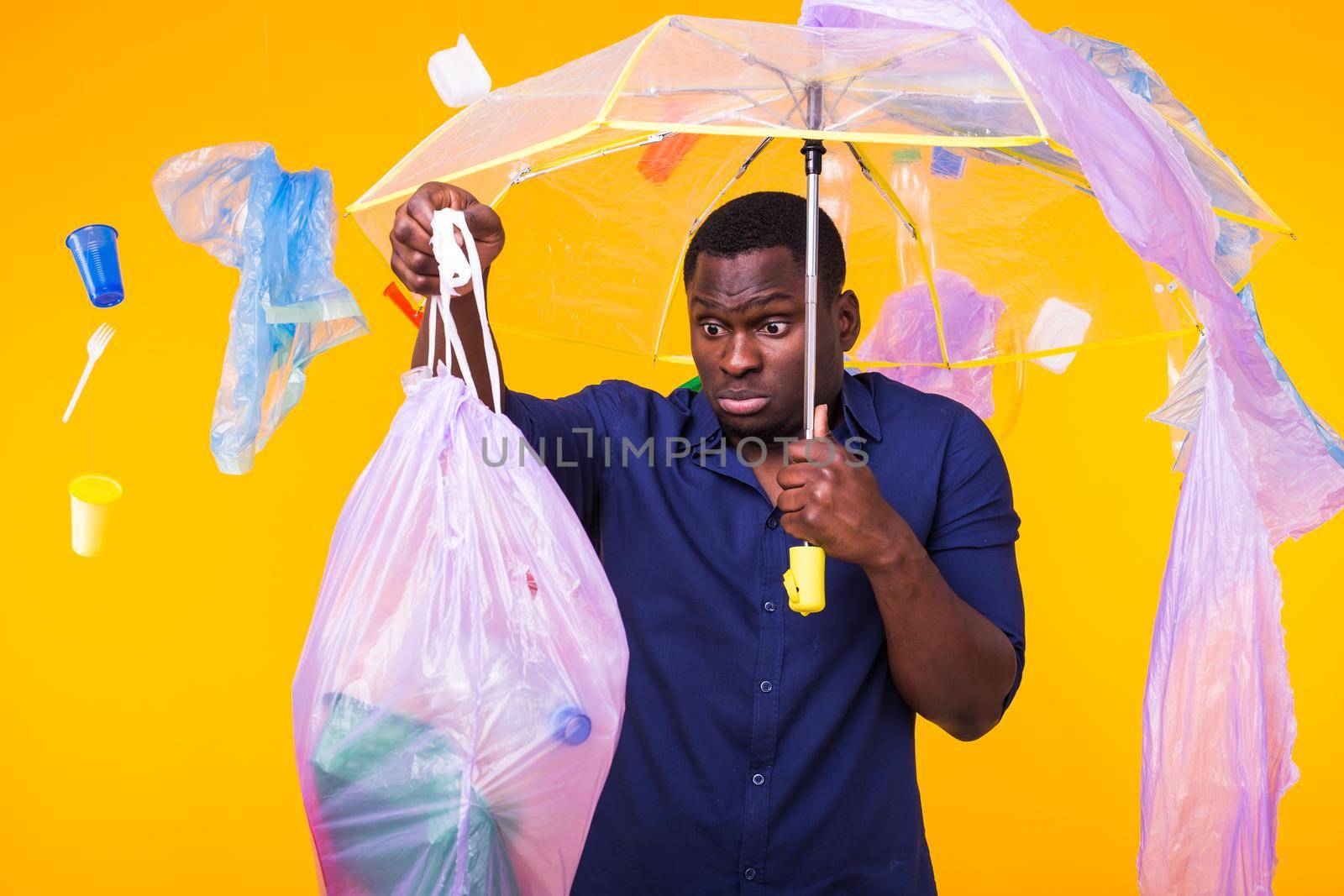 Plastic recycling problem, ecology and environmental disaster concept - Surprised african american man on yellow background with trash. He is worried about ecology disaster by Satura86