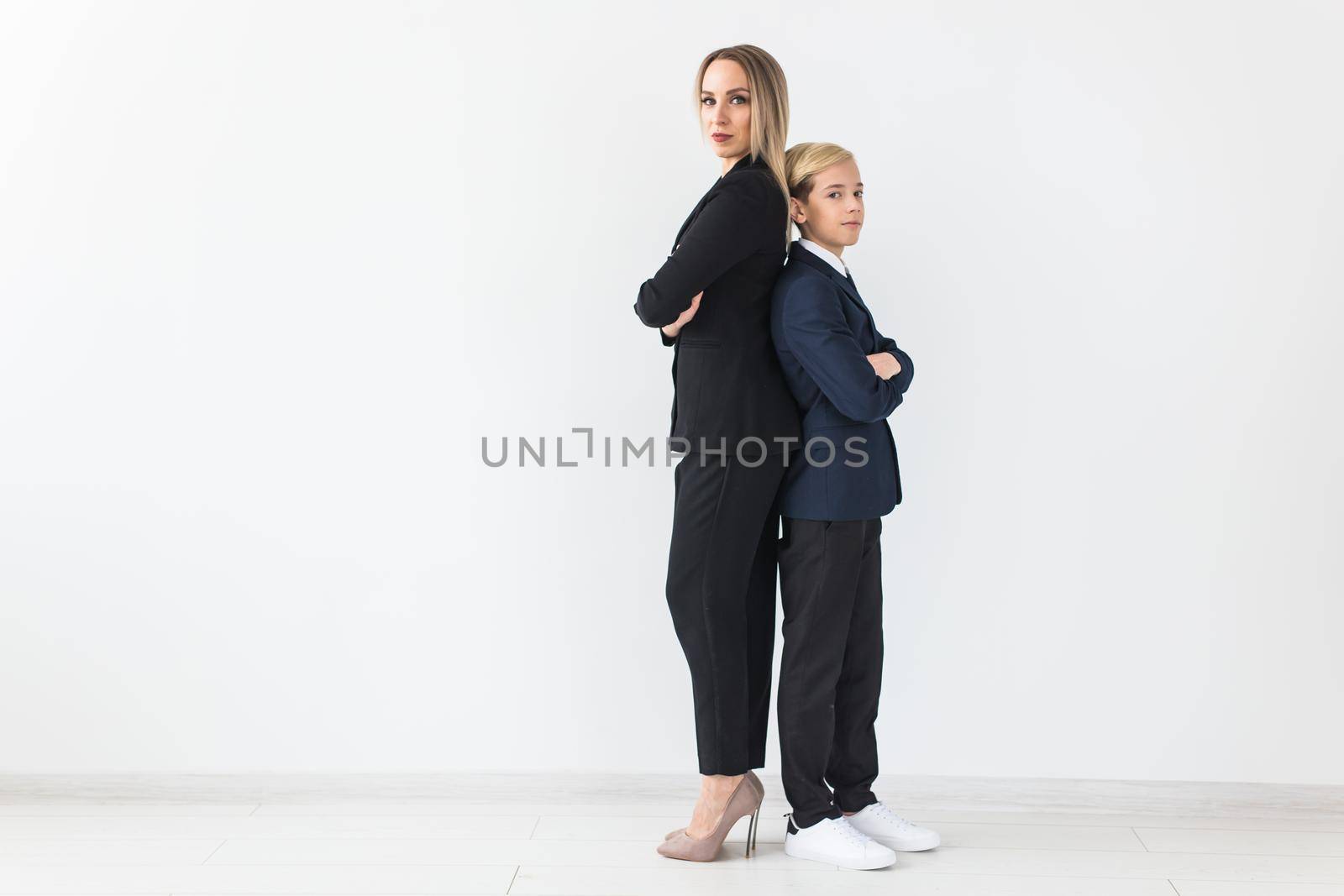 Teenager and single parent - Young mother and son standing together, back to back on white background with copyspace.