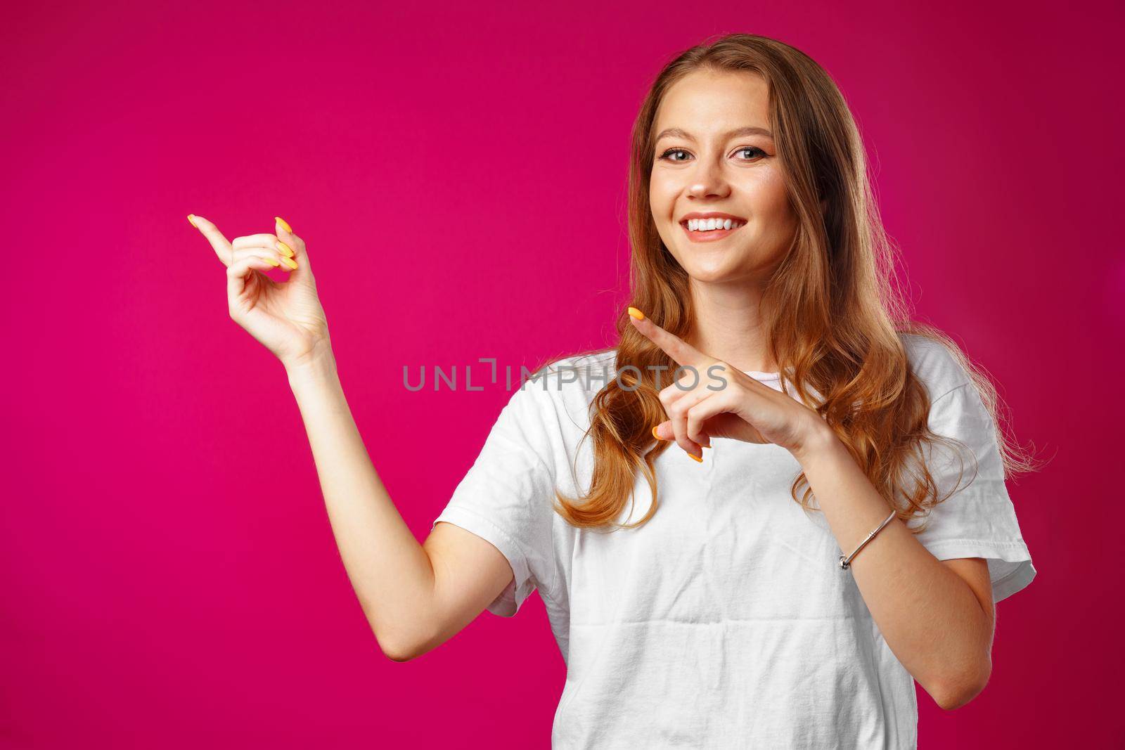 Portrait charming pretty cheerful girl showing copy space with her finger