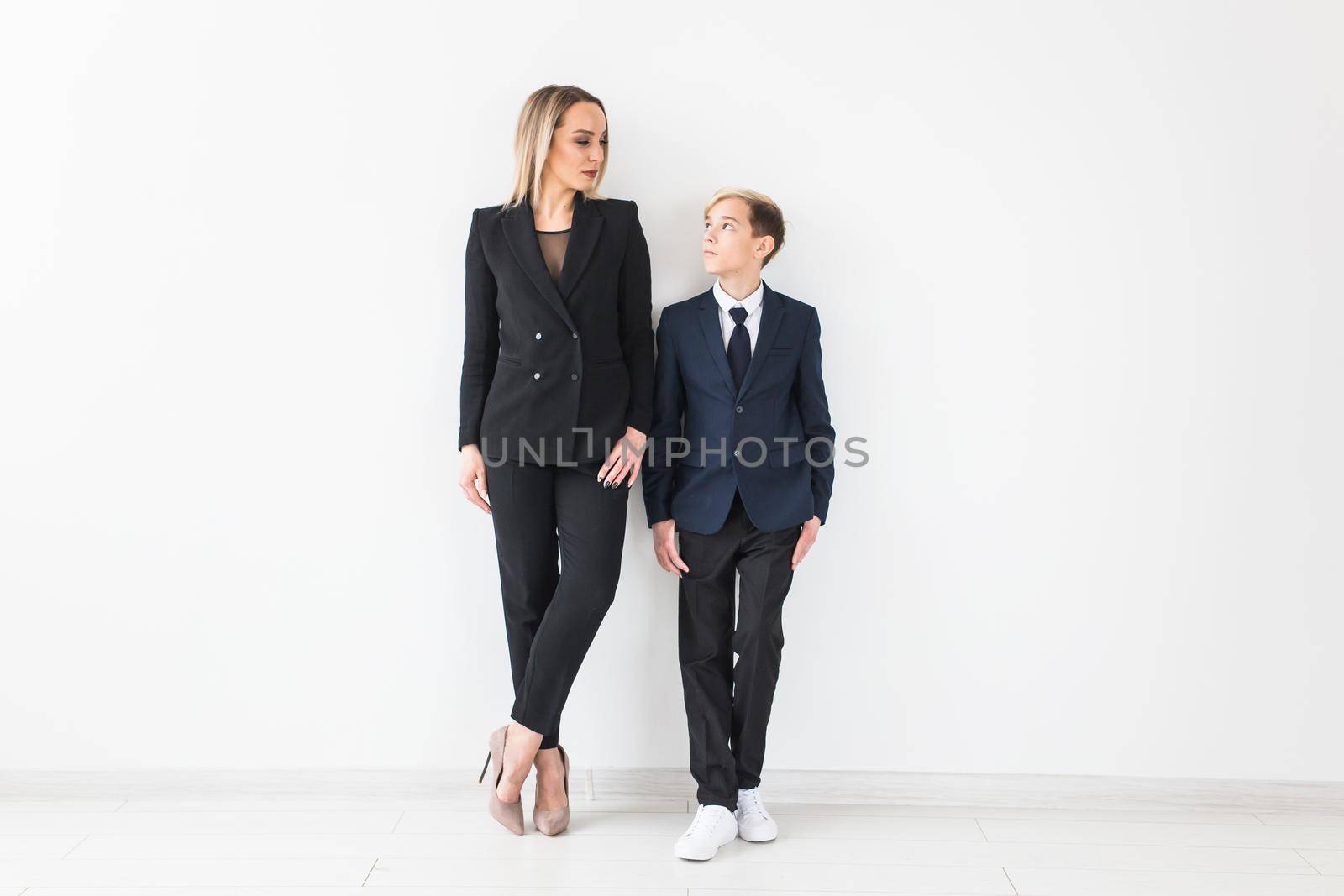 Teenager and single parent - Young mother and son standing together on white background. by Satura86