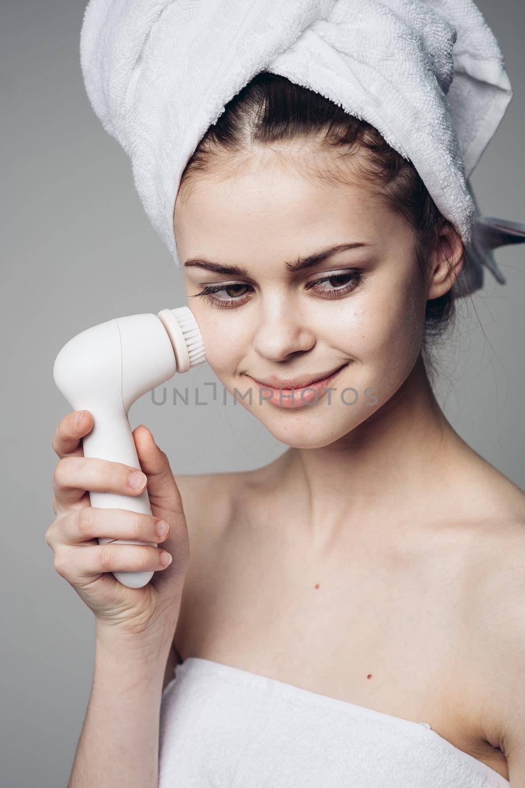 woman with towel on head facial massager skin care hygiene. High quality photo