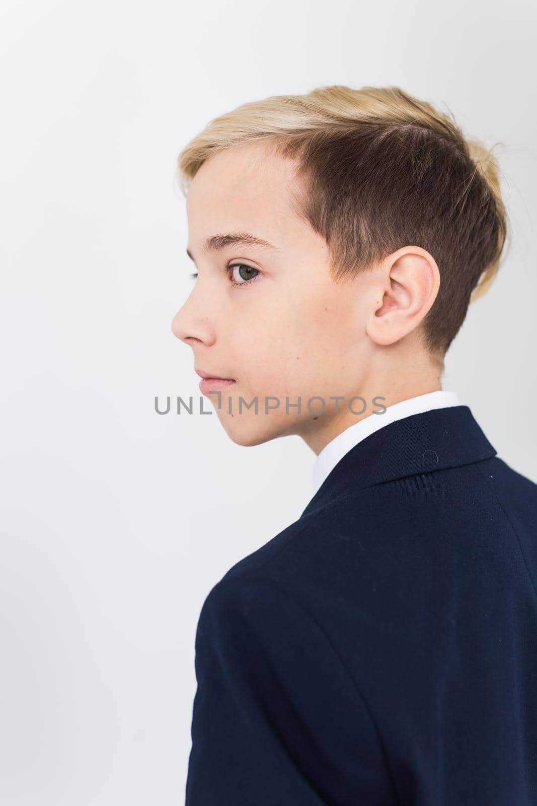 Portrait of stylish school boy teenager in white shirt and jacket against white background with copy space