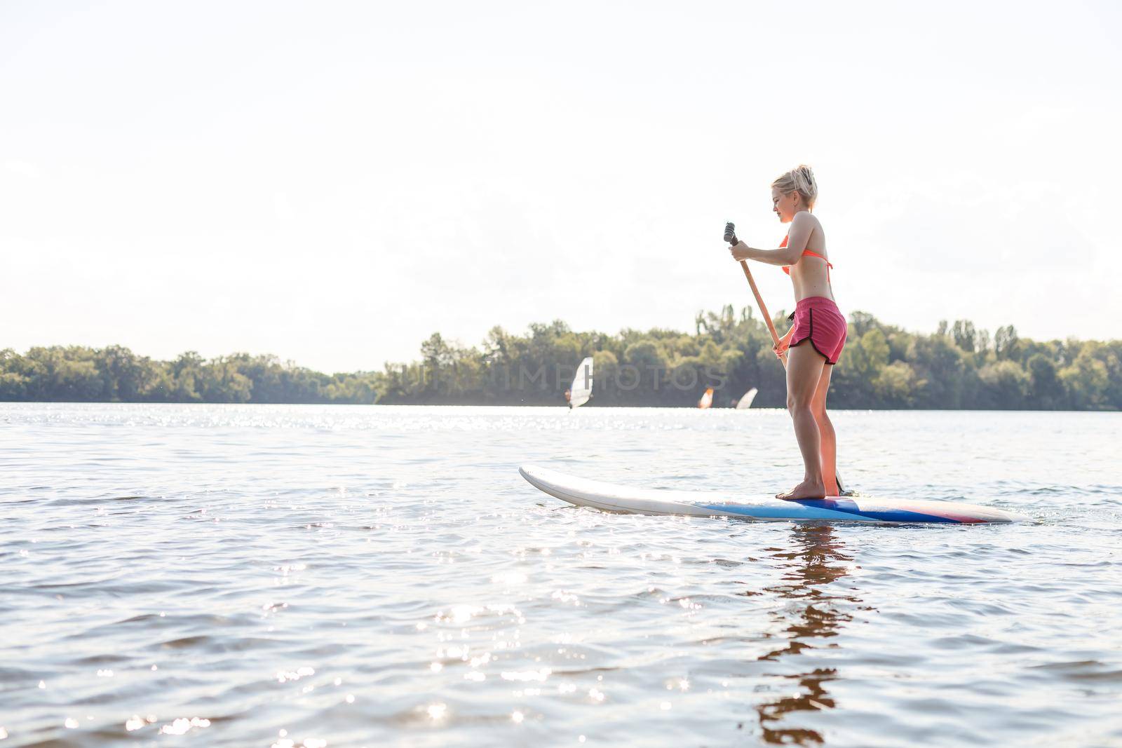 Young attractive woman on stand up paddle board in the lake, SUP