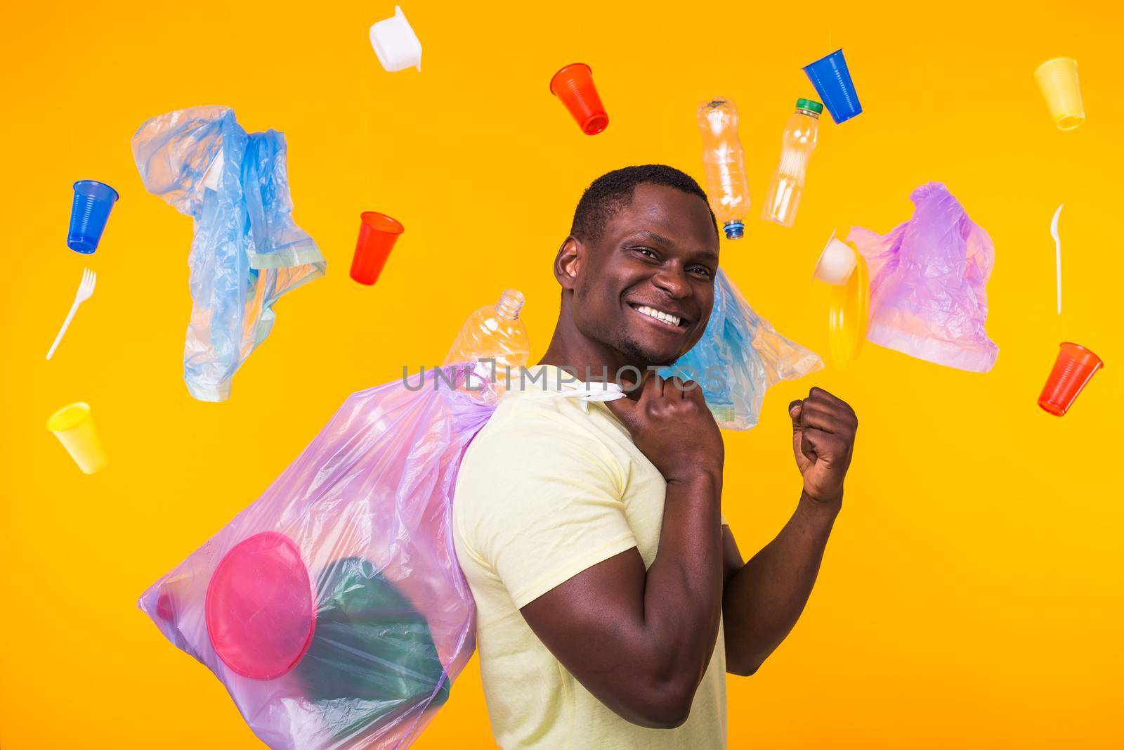 Problem of trash, plastic recycling, pollution and environmental concept - confused man carrying garbage bag on yellow background.