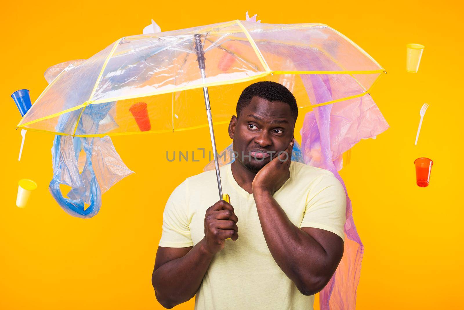 Problem of trash, plastic recycling, pollution and environmental concept - pensive african american man on yellow background with garbage. by Satura86