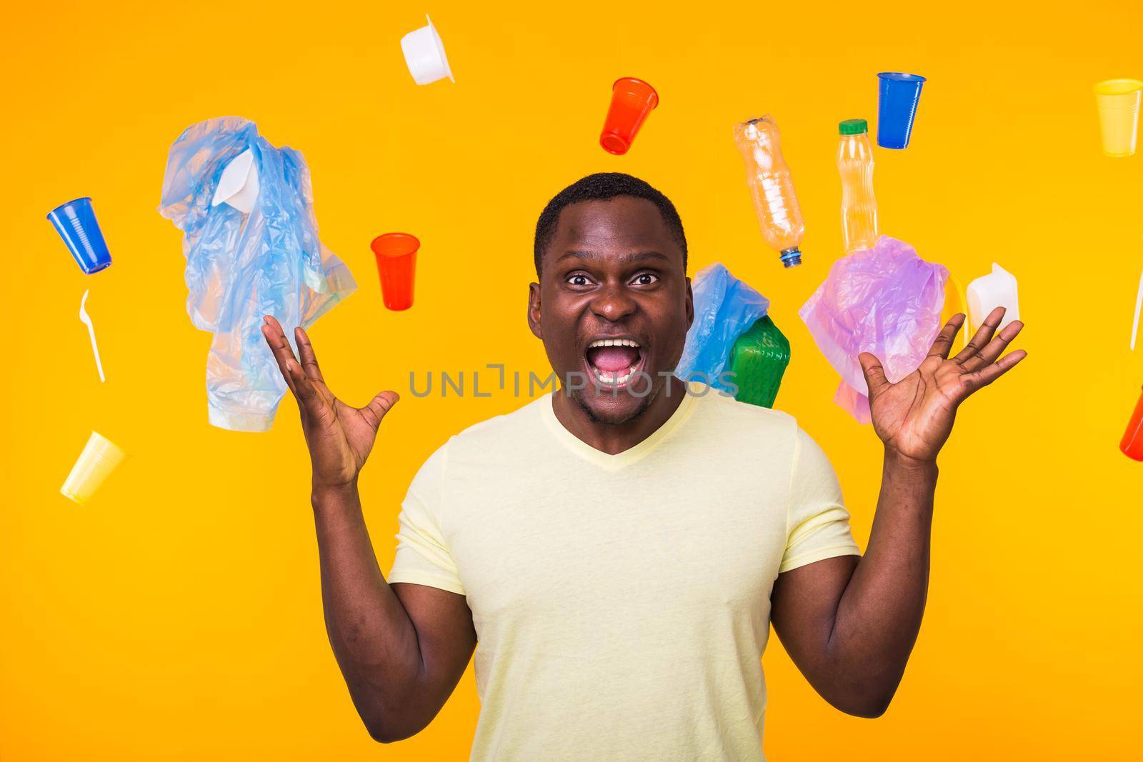 World Environment Day, plastic recycling problem and environmental disaster concept - Terrified man on yellow background with trash by Satura86