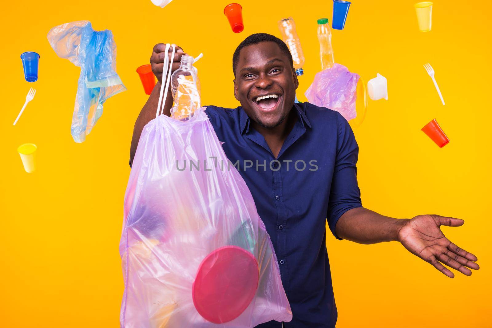 Problem of trash, plastic recycling, pollution and environmental concept - confused man carrying garbage bag on yellow background.