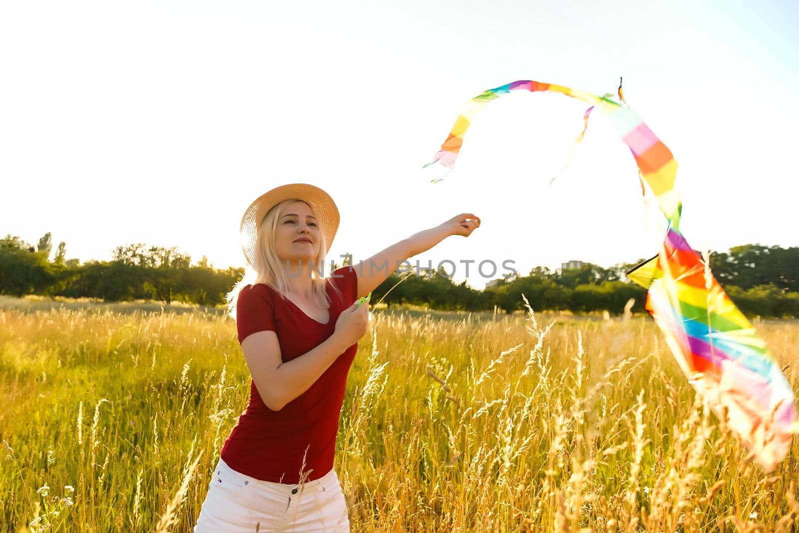 Portrait of a young and carefree woman launching kite on the greenfield. Concept of active lifestyle in nature