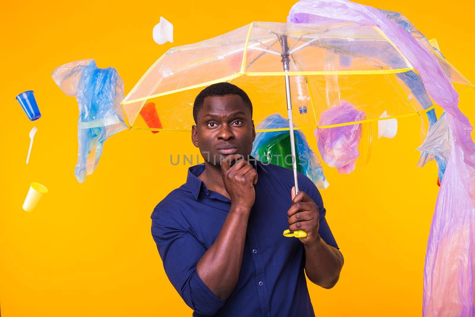 Problem of trash, plastic recycling, pollution and environmental concept - pensive african american man on yellow background with garbage. by Satura86