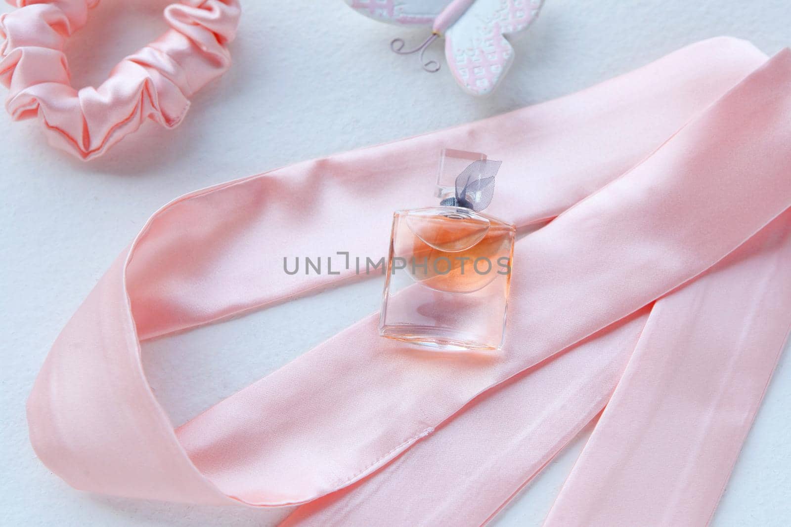 Pink women's perfume in beautiful bottle and white flower on pink background