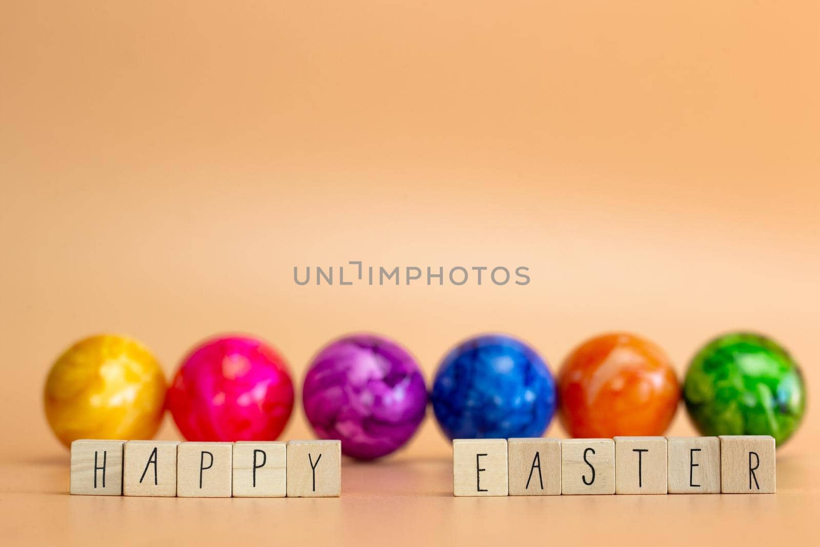 Happy Easter written with pastel colored orange background and colorful fainted Easter eggs, Bright fresh colors, Spring,Easter Holiday, greeting card concept with copy space space for text