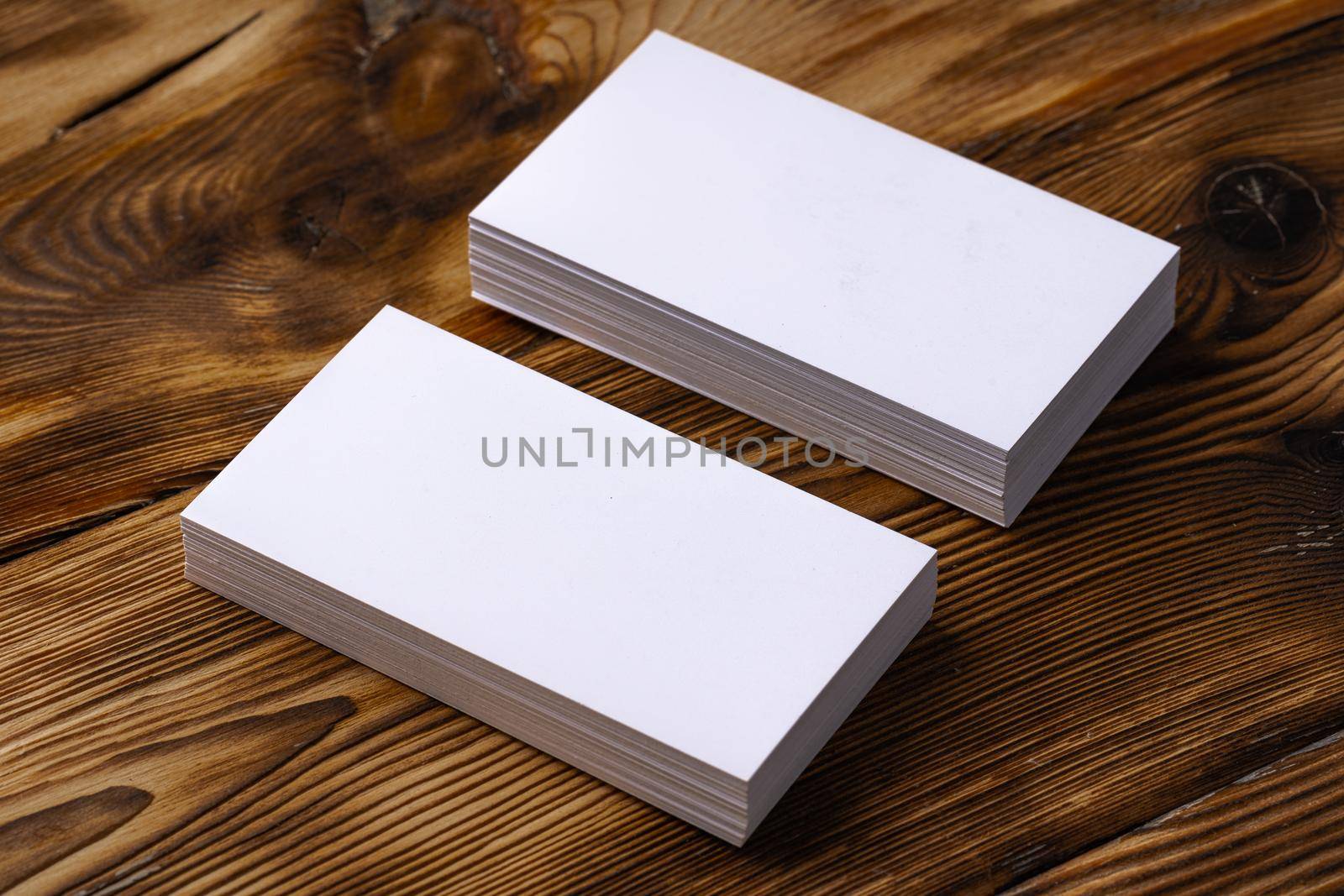 Stack of white business cards on brown wooden background, close up