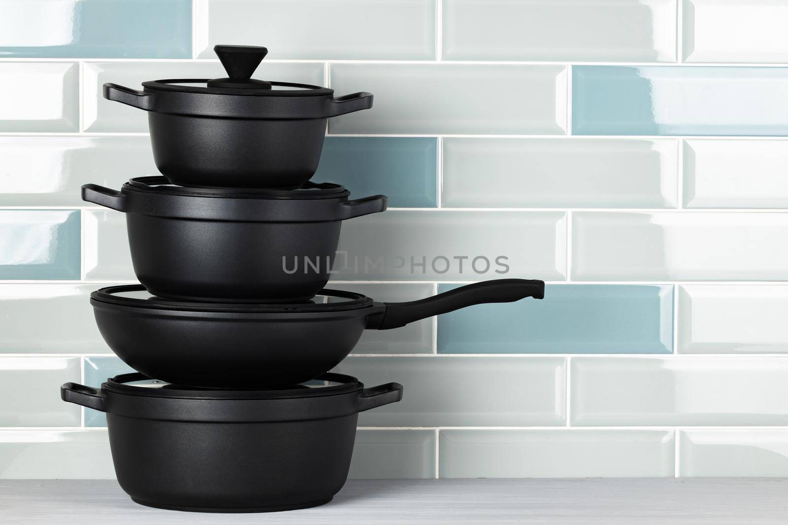 New black cookware against blue tile wall close up