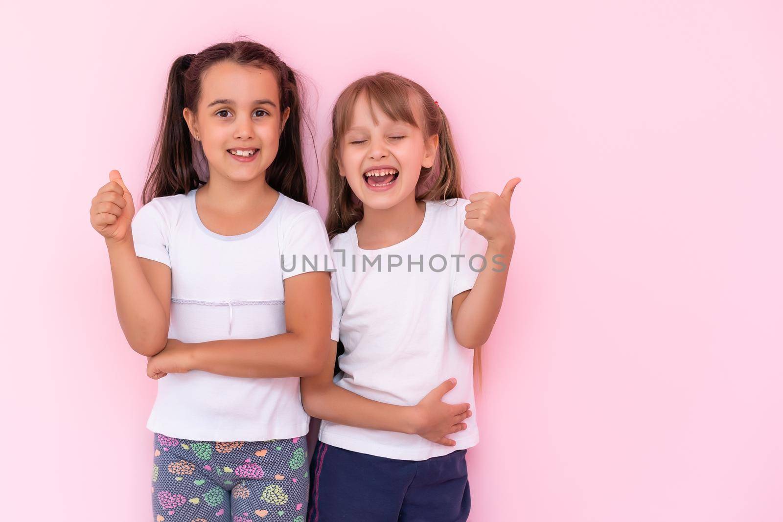 Two little girls - best friends, isolated over on a pink background