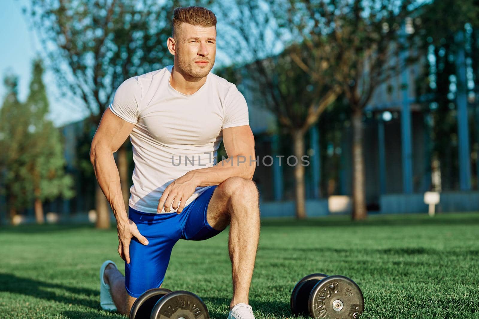 athletic man training with dumbbells in the morning Park by Vichizh