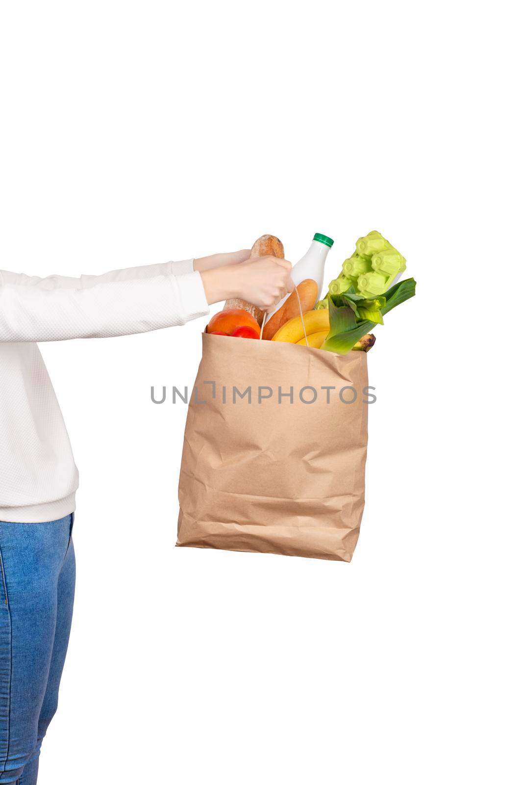 Food delivery or donation concept. Grocery store shoping. Girl holds a paper bag filled with groceries such as fruits, vegetables, milk, yogurt, eggs isolated on white.