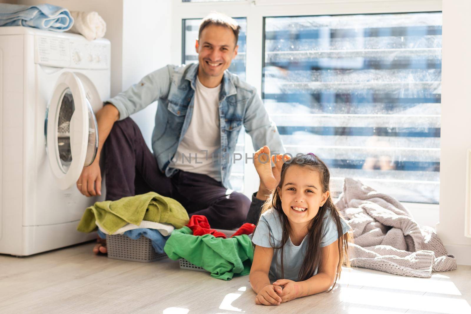 Happy Family loading clothes into washing machine in home by Andelov13