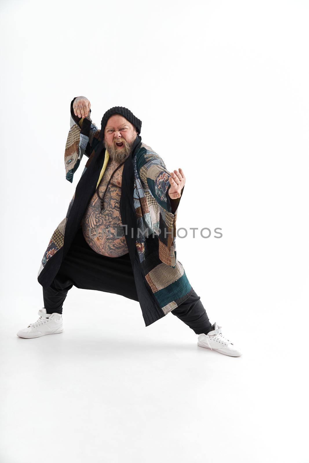 Fat stylish bearded tattoed caucasian man with big belly is posing and dancing wearing ethnic kimono by Yaroslav_astakhov