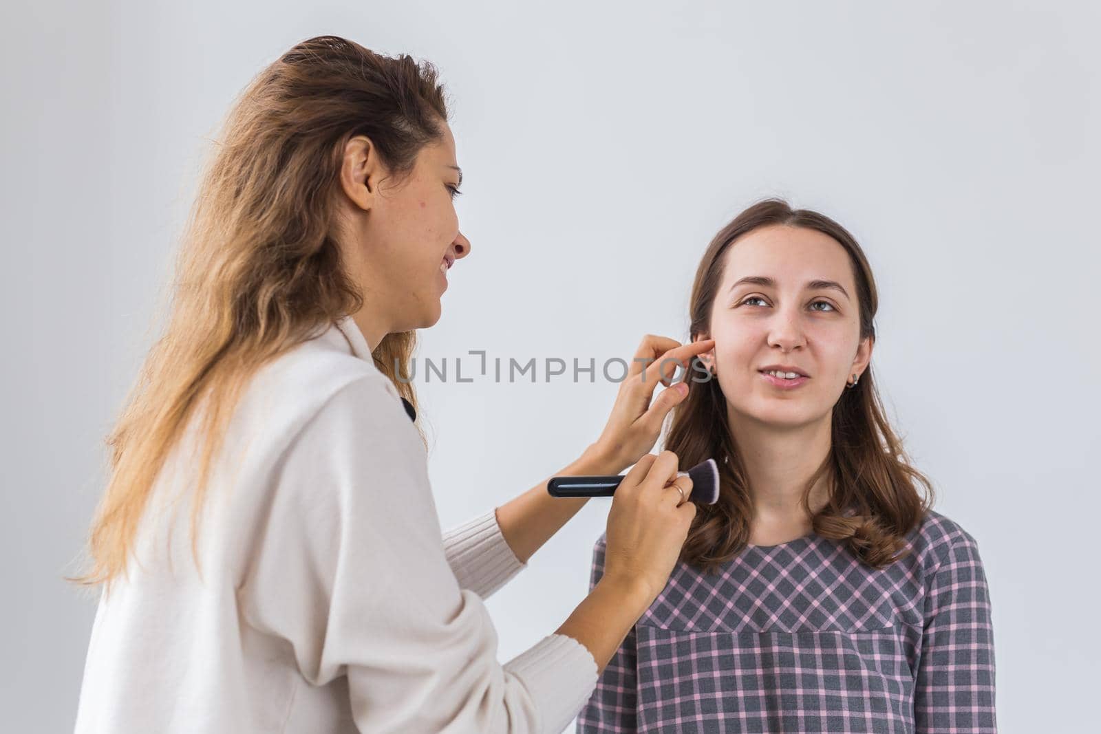 Beauty and cosmetics concept - Makeup artist doing professional make up of young woman.