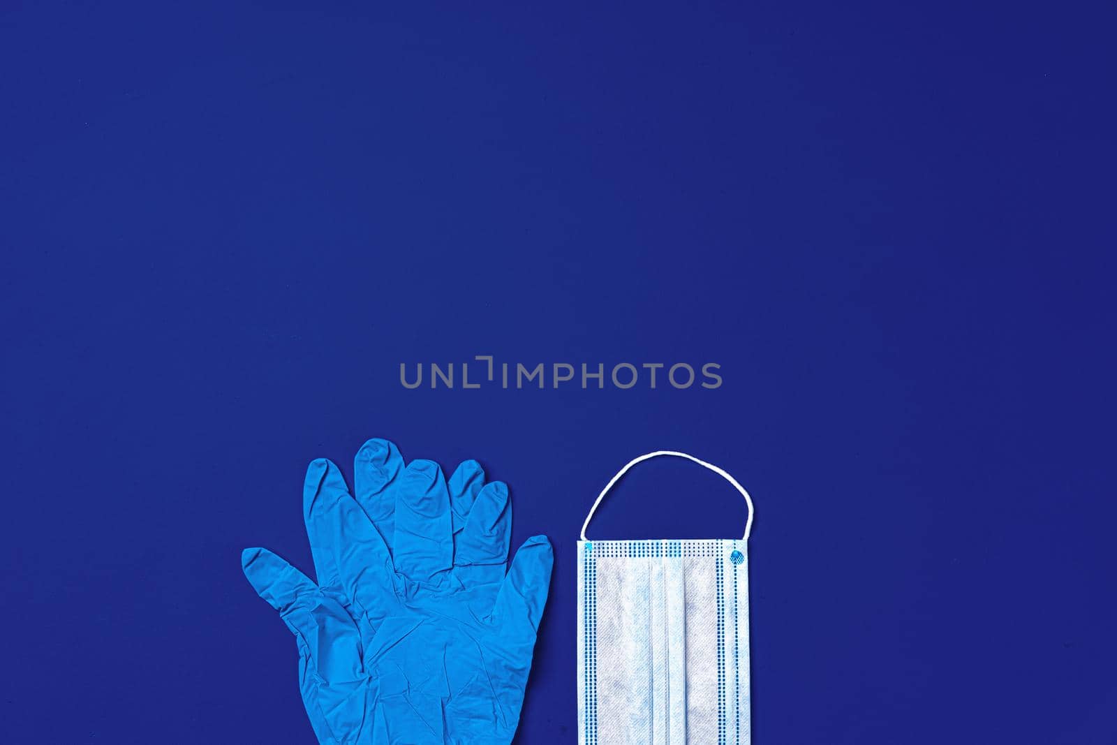 Medical gloves and surgical protective face mask on dark blue background. Coronavirus concept