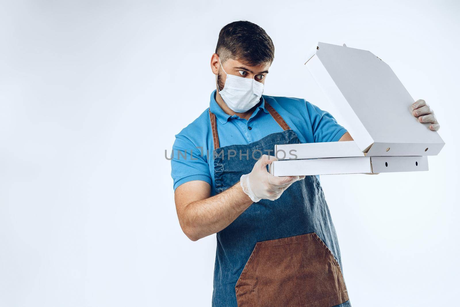 Pizza delivery man in medical gloves and mask against grey background. Safe service while coronavirus covid-19 outbreak