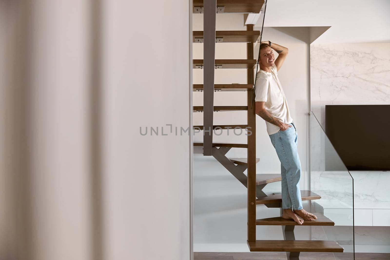 Relaxing happy caucasian man on the minimalistic stairs in modern light apartment