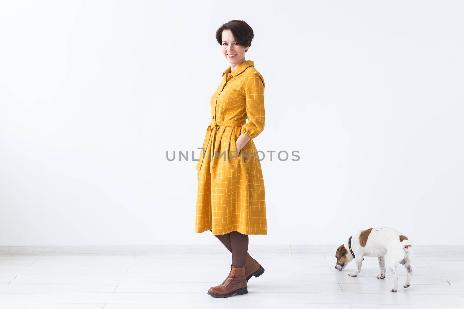 Cheerful young woman posing in a yellow dress with her beloved dog Jack Russell Terrier standing on a white background. The concept of casual wear and pets by Satura86