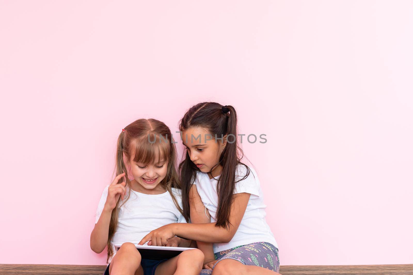 Little girls playing on a tablet computing device on the floor by Andelov13