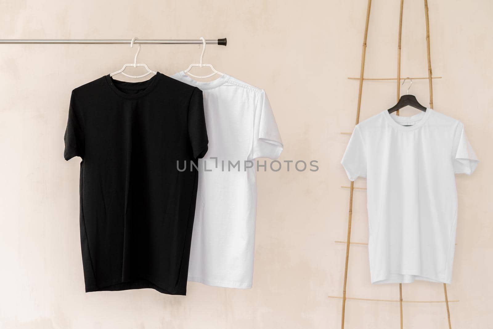 White and black T-shirts on hangers for design presentation, copy space