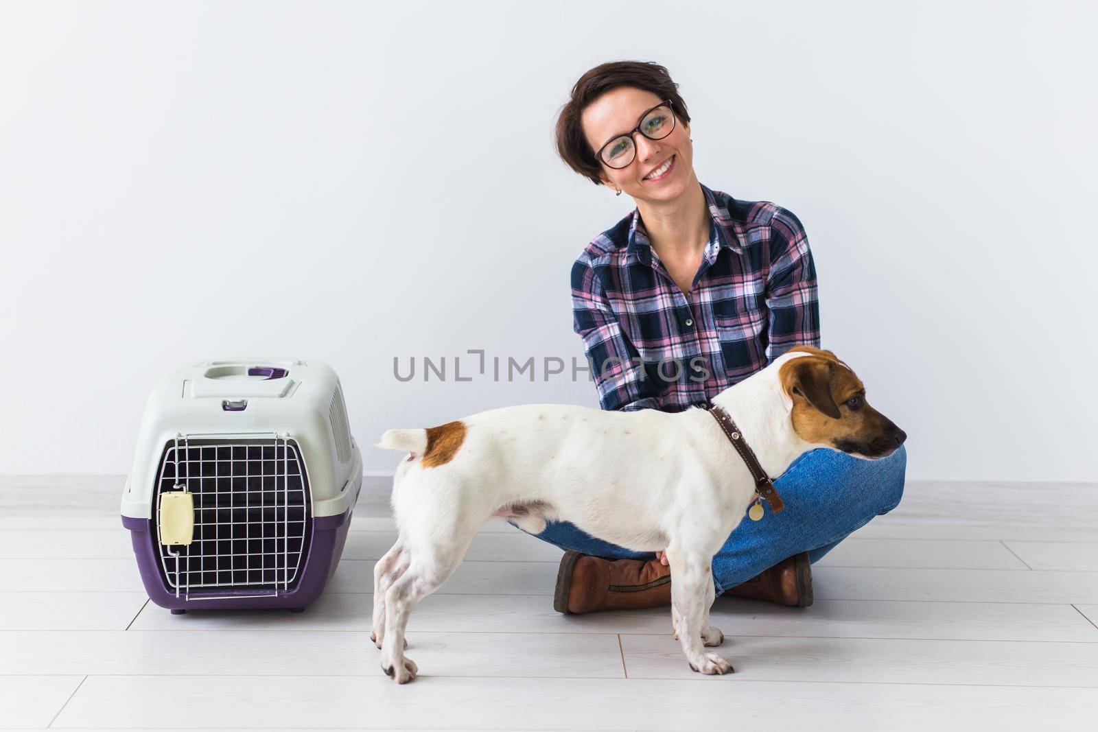 Dog carrying bags and pets owner concept - Attractive cheerful female in plaid shirt holds favourite pet. Happy woman with her jack russell terrier.