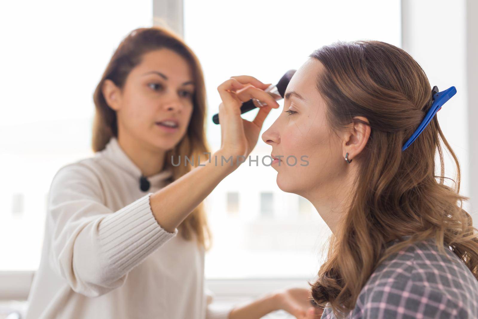 Beauty and cosmetics concept - Makeup artist doing professional make up of young woman.