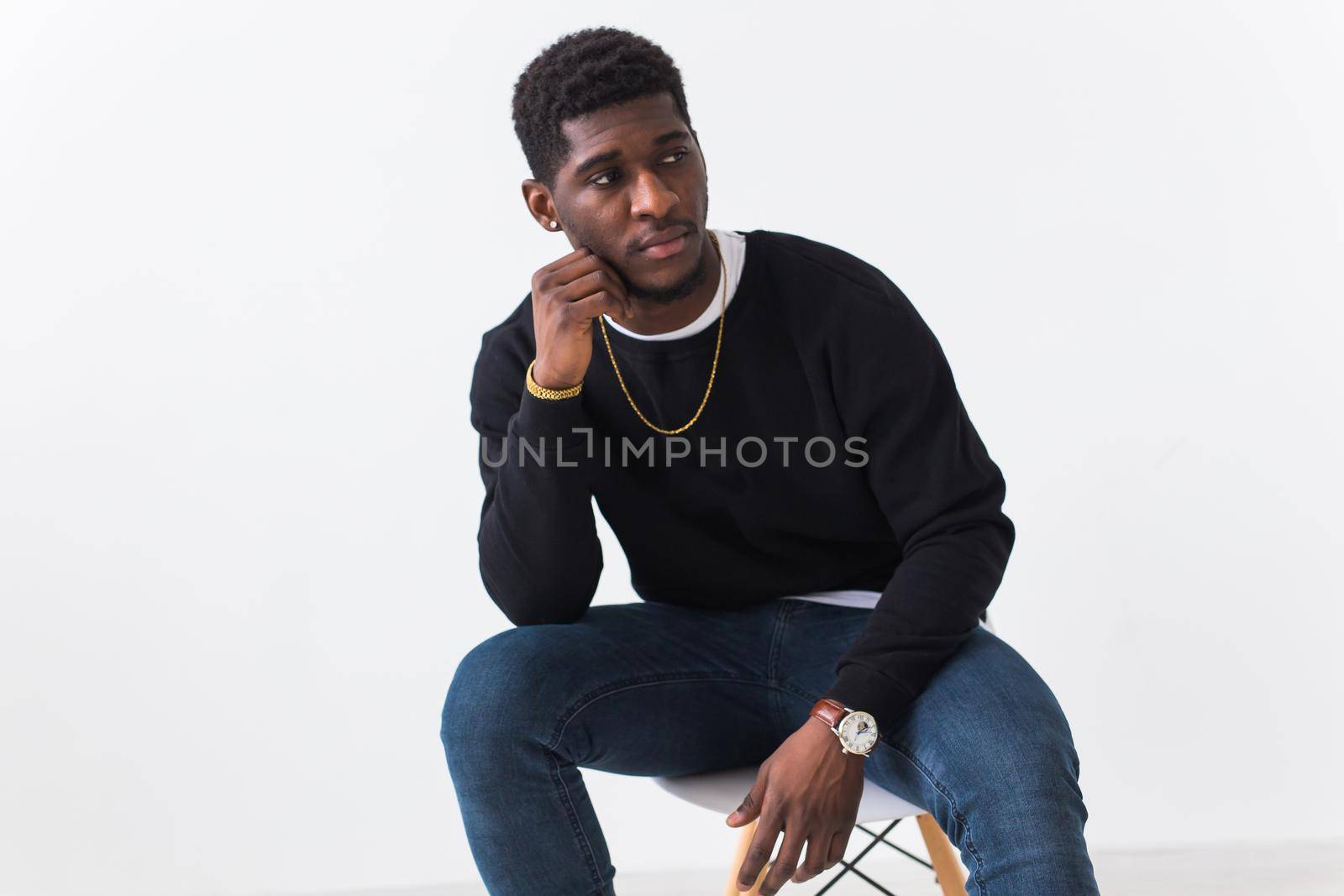 Studio shot of young handsome African man wearing hoodie against white background.