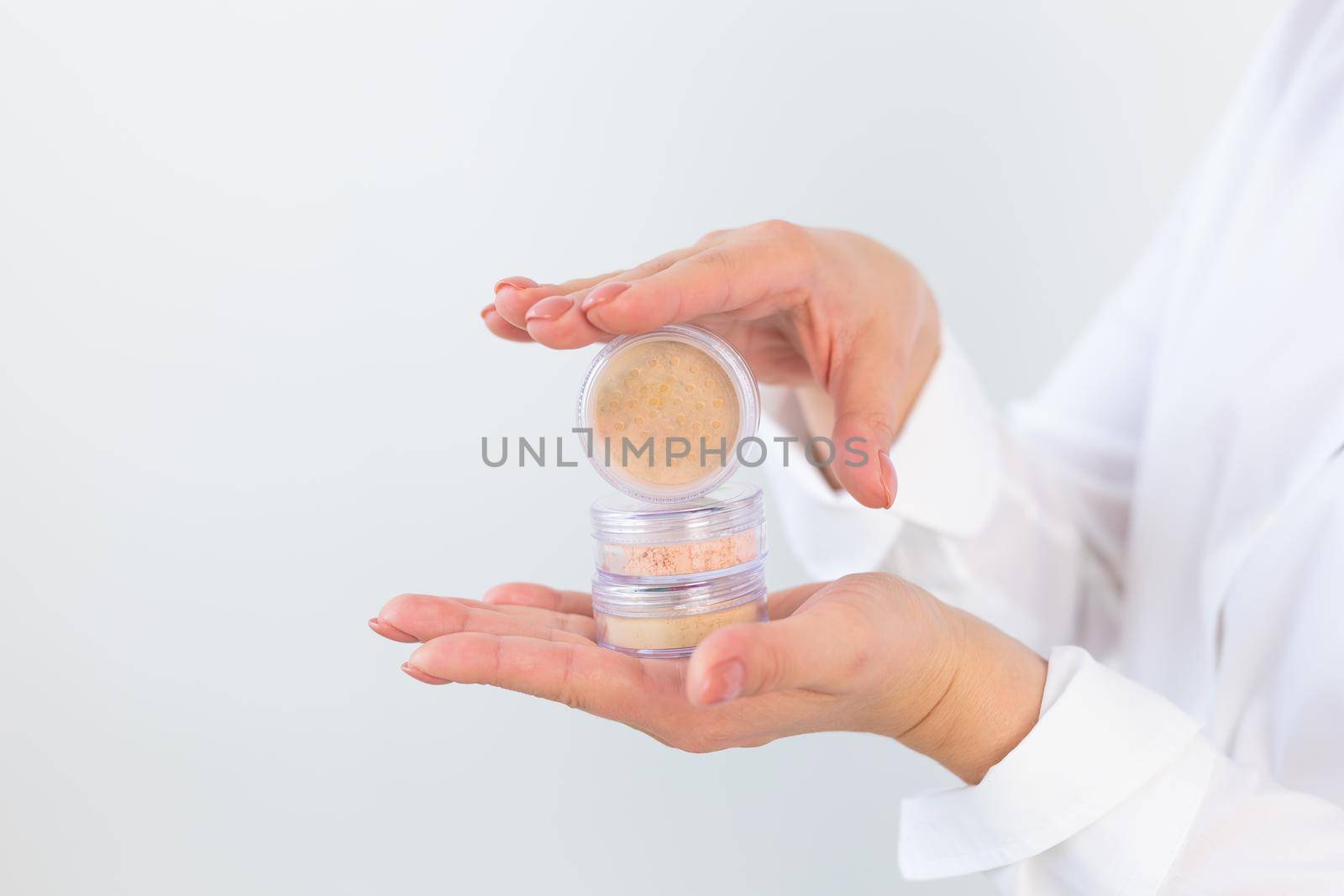 Female hands holding face powder on a white background. Isolated background. Space for text by Satura86