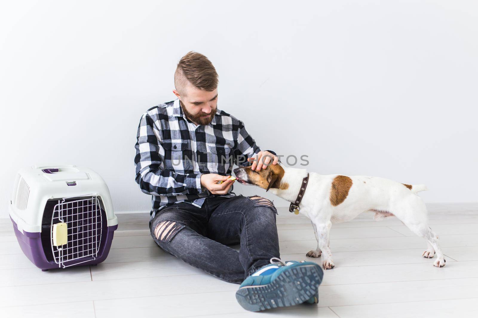 Dog carrying bags and pets owner concept - Attractive cheerful male in plaid shirt holds favourite pet. Happy bearded man with his jack russell terrier.