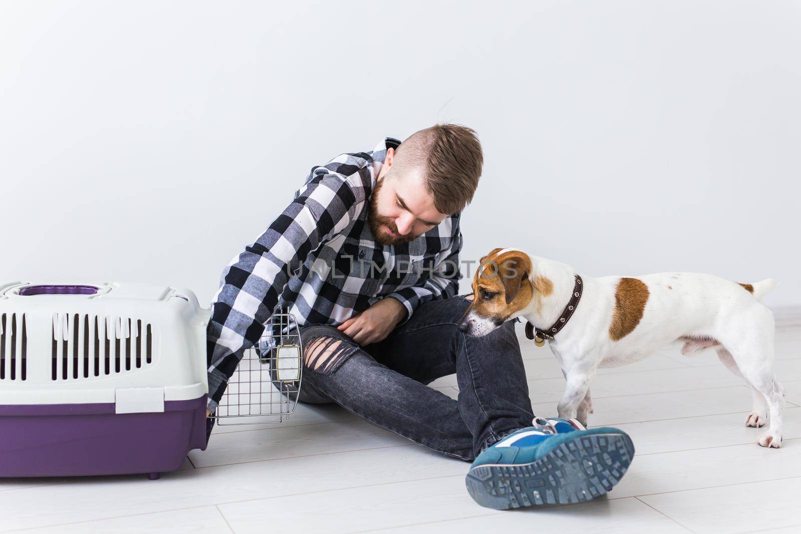 Dog carrying bags and pets owner concept - Attractive cheerful male in plaid shirt holds favourite pet. Happy bearded man with his jack russell terrier by Satura86