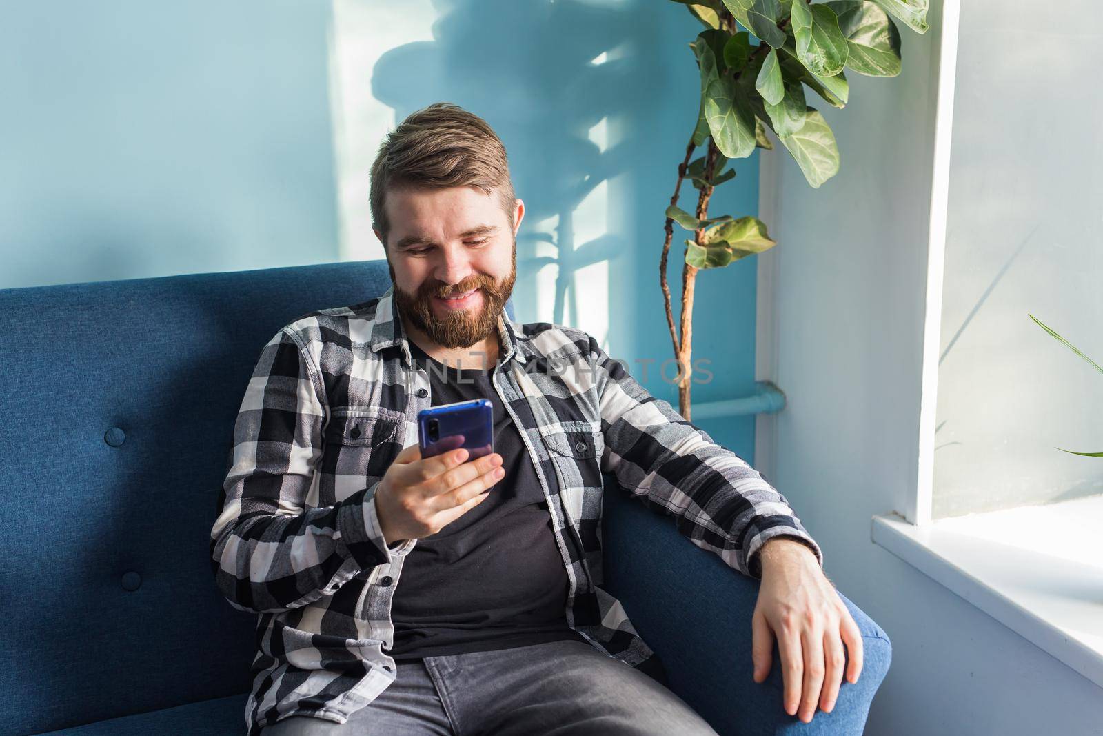 Man playing online games with a smart phone sitting on a couch at home