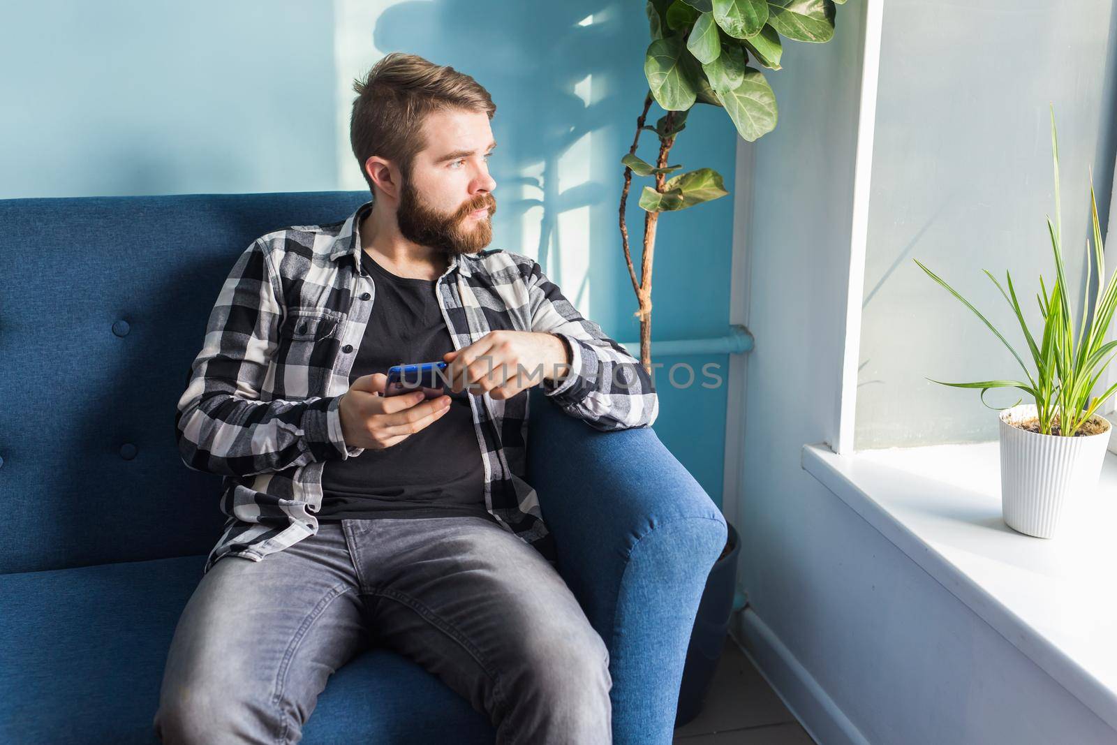 Man playing online games with a smart phone sitting on a couch at home