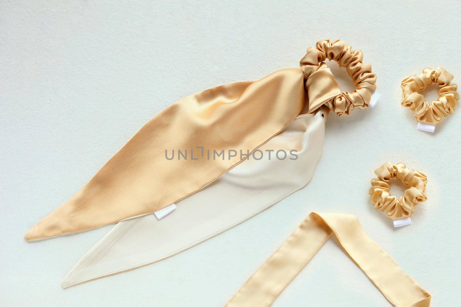 golden silk scrunchy flat lay on white. Hairdressing tools and accessories. luxury ladyes Hair Scrunchie, Elastic Hair Band, Bobble Sport Scrunchie Hairband. hair scarf fixed on the scrunchie