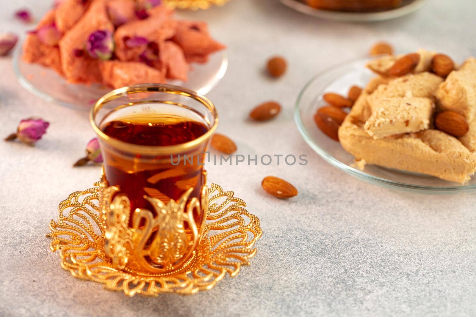 Assortment of Turkish delights with glass of tea on gray background, close up