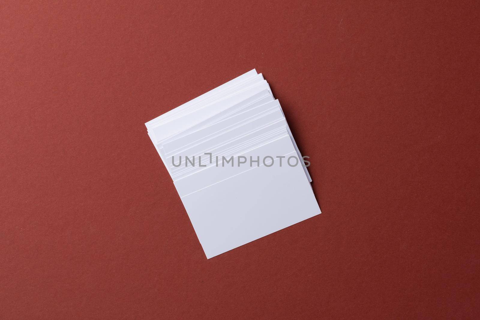 Blank white business cards on burgundy paper background, top view
