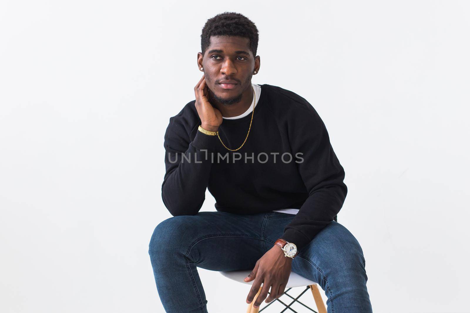 Handsome African American man posing in black hoodie on a white background. Youth street fashion photo with afro hairstyle