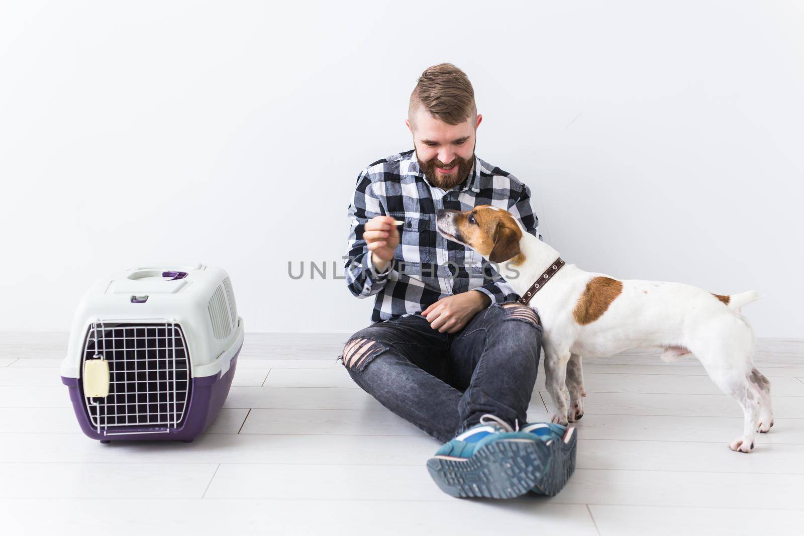 Dog carrying bags and pets owner concept - Attractive cheerful male in plaid shirt holds favourite pet. Happy bearded man with his jack russell terrier by Satura86