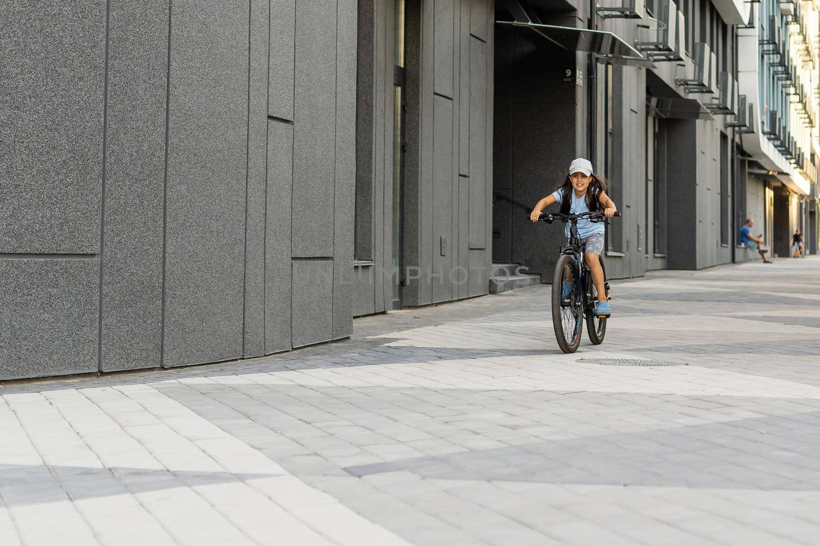 Adorable little girl riding a bike in a city