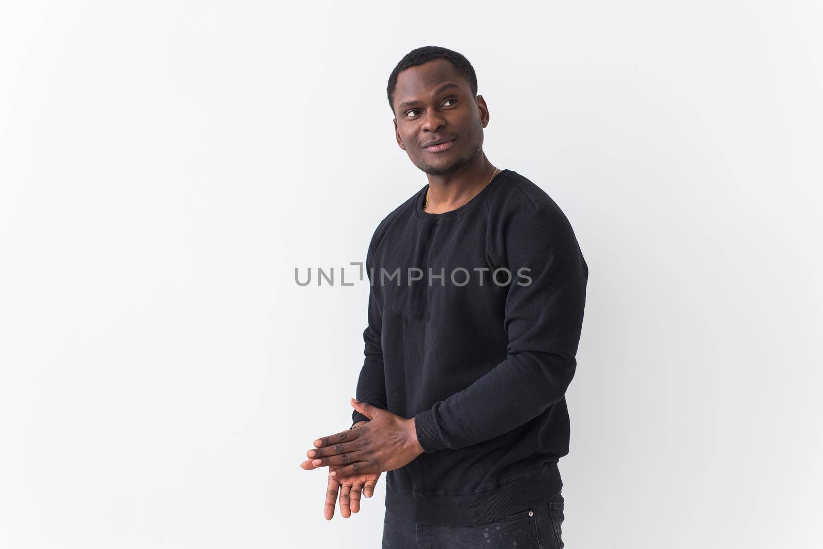 Handsome African American man posing in black sweatshirt on a white background with copyspace. Youth street fashion photo with afro hairstyle. by Satura86