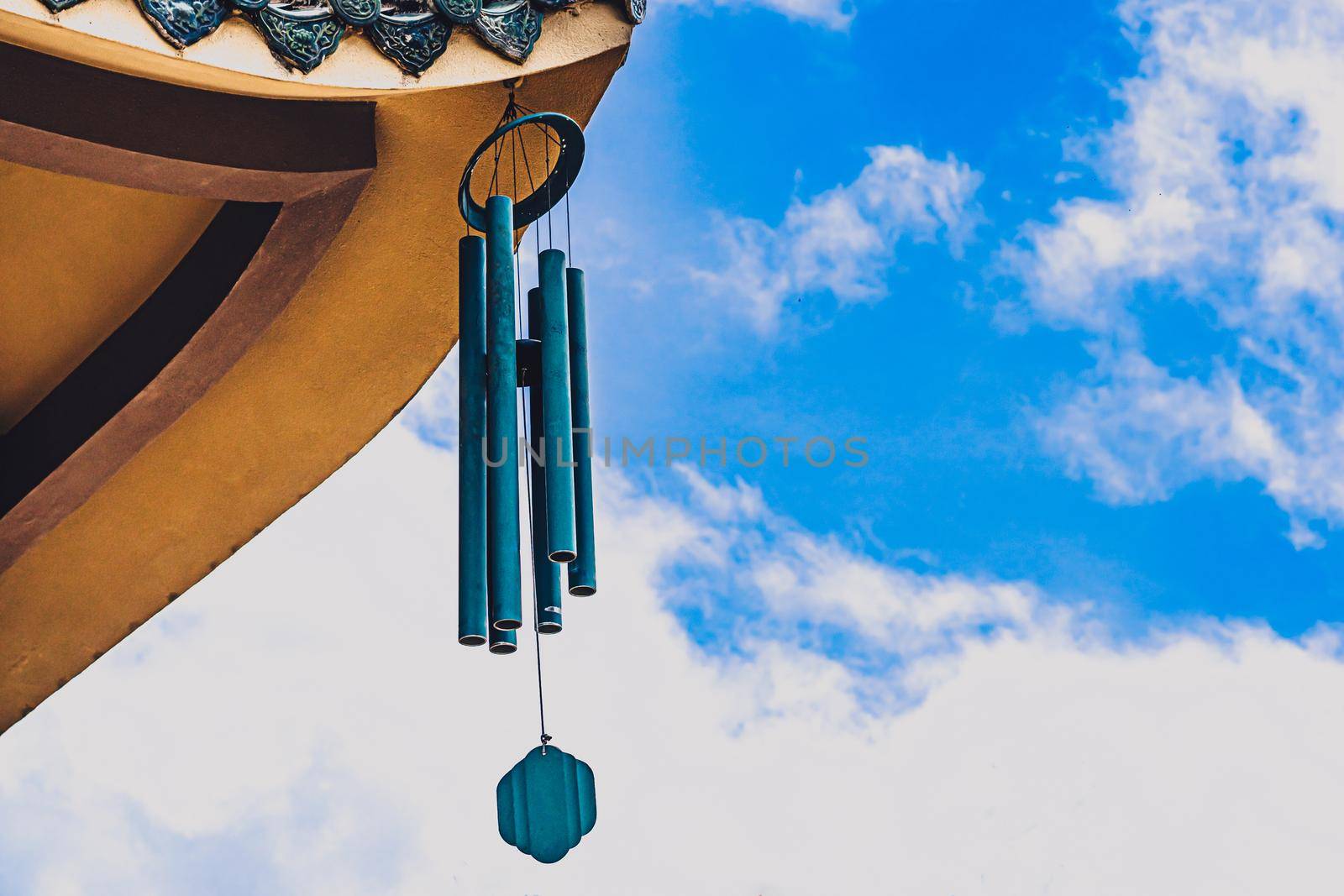E Pagoda curved roof building temple, metal big hanging wind sound bell chime effect melodious buddhism china. Day blue sky clouds background. Calm god religious peace quiet relax soul health mood.