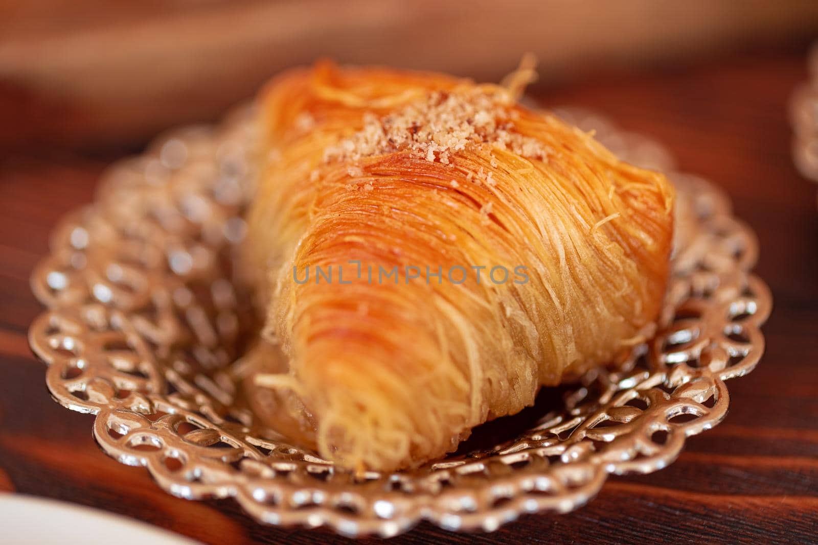 Turkish sweets on small plate on brown wooden background, close up