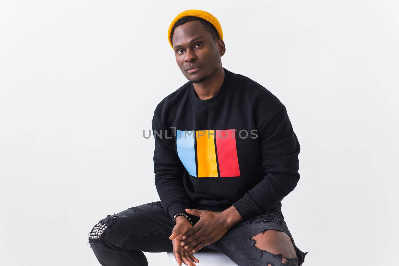 Handsome African American man posing in black hoodie on a white background. Youth street fashion photo with afro hairstyle