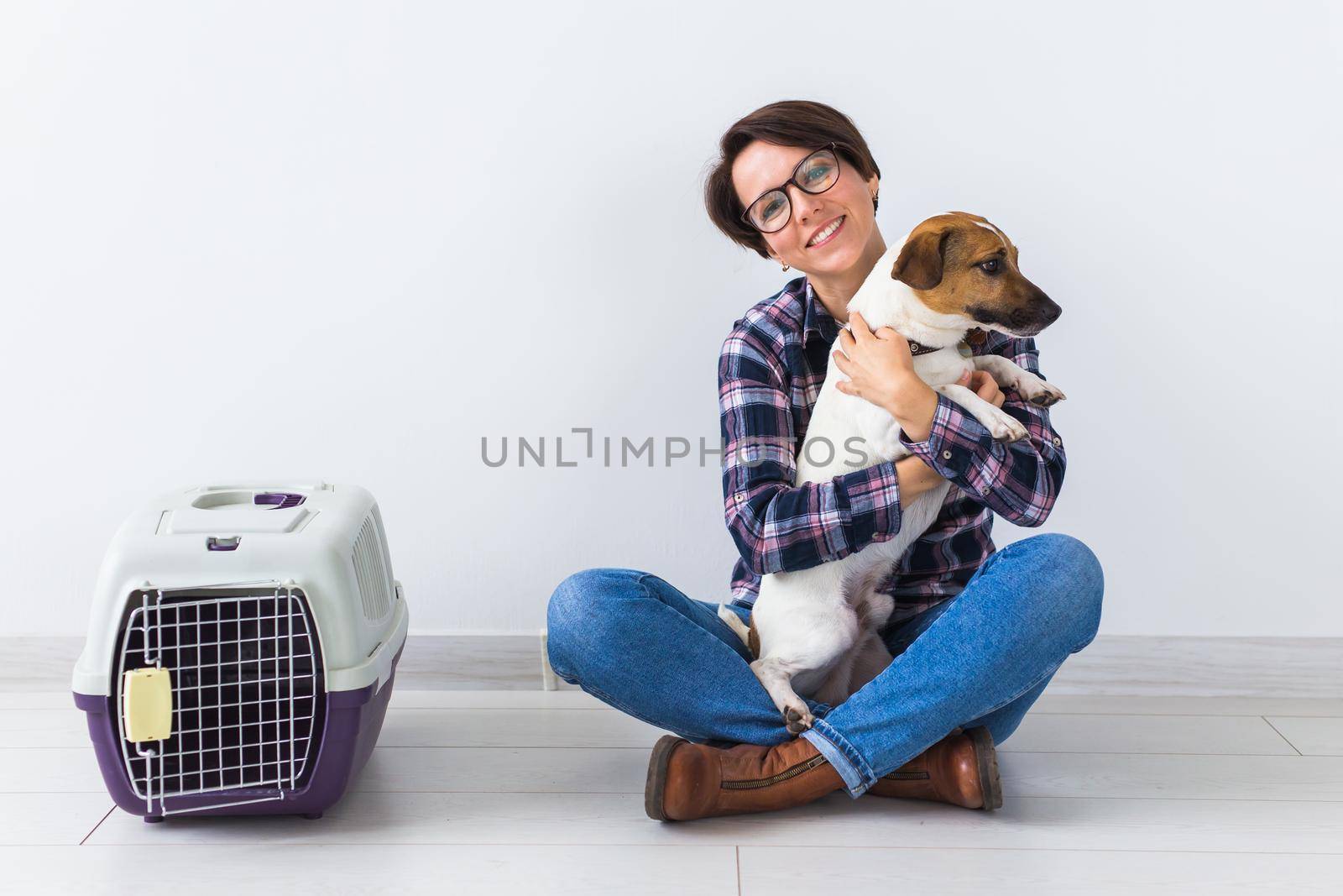 Dog carrying bags and pets owner concept - Attractive cheerful female in plaid shirt holds favourite pet. Happy woman with her jack russell terrier.