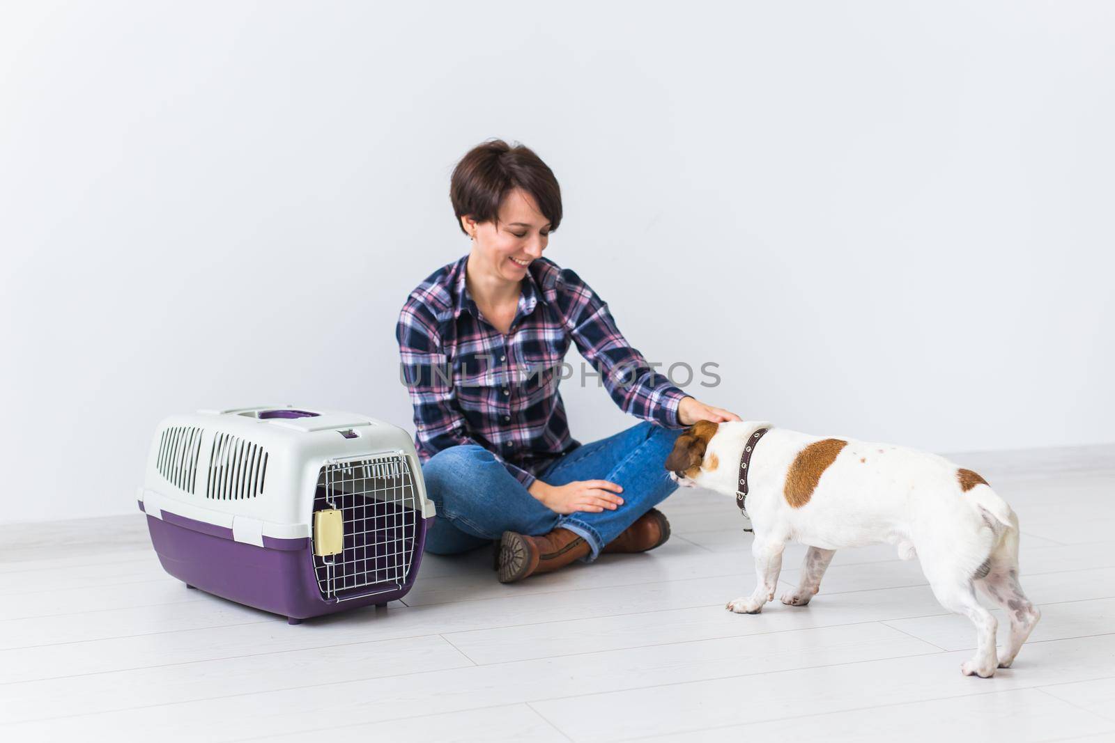 Dog carrying bags and pets owner concept - Attractive cheerful female in plaid shirt holds favourite pet. Happy woman with her jack russell terrier.